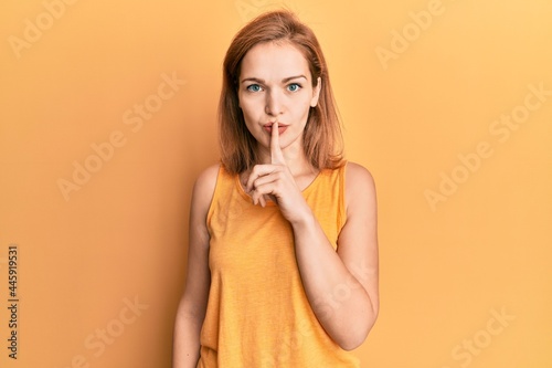 Young caucasian woman wearing casual style with sleeveless shirt asking to be quiet with finger on lips. silence and secret concept.