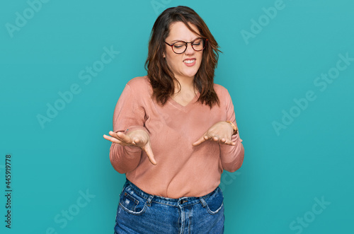 Young plus size woman wearing casual clothes and glasses disgusted expression, displeased and fearful doing disgust face because aversion reaction.