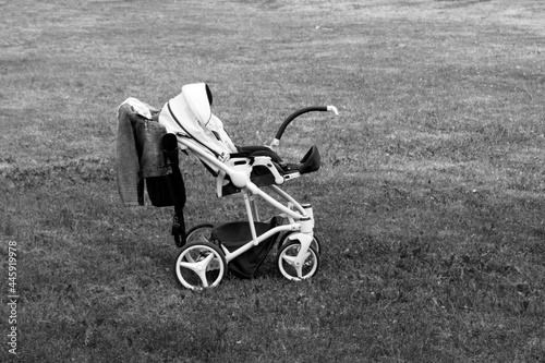 A white baby stroller on a summer glade, black and white photo