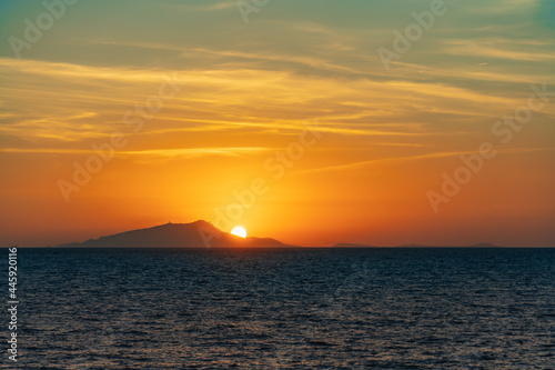 Beautiful sunset with sun hiding behind Ischia island over Tyrrhenian Sea photo