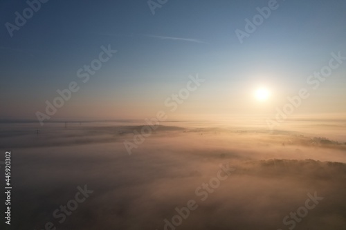 Fog landscape above the clouds at sunrise. Mystical weather after wet night. Forests and power poles. Aerial view. Germany.