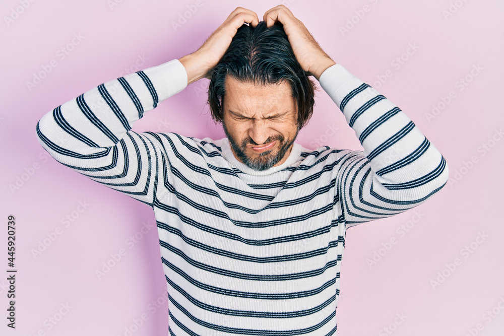 Middle age caucasian man wearing casual clothes suffering from headache desperate and stressed because pain and migraine. hands on head. Middle age caucasian man wearing casual clothes suffering from headache desperate and stressed because pain and migraine. hands on head.