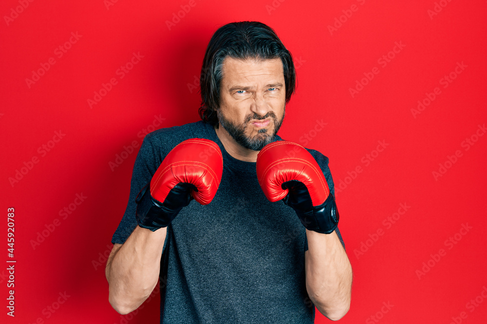 Middle age caucasian man using boxing gloves skeptic and nervous, frowning upset because of problem. negative person.