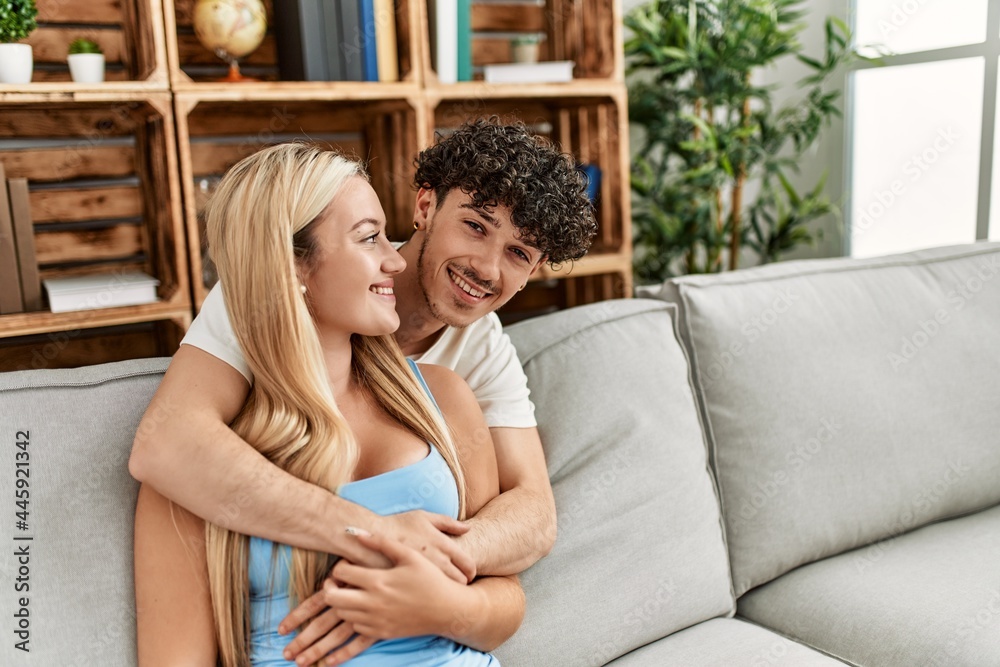 Young couple sitting on the sofa hugging at home. Young couple sitting on the sofa hugging at home.