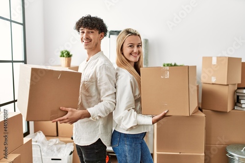 Young beautiful couple smiling happy holding cardboard box at new home.