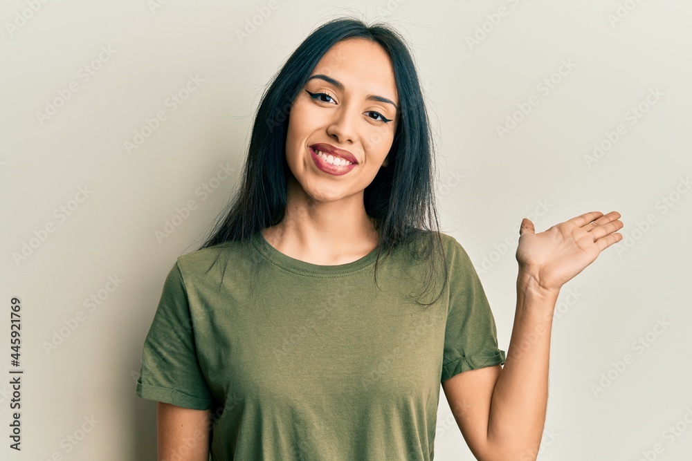 custom made wallpaper toronto digitalYoung hispanic girl wearing casual t shirt smiling cheerful presenting and pointing with palm of hand looking at the camera.