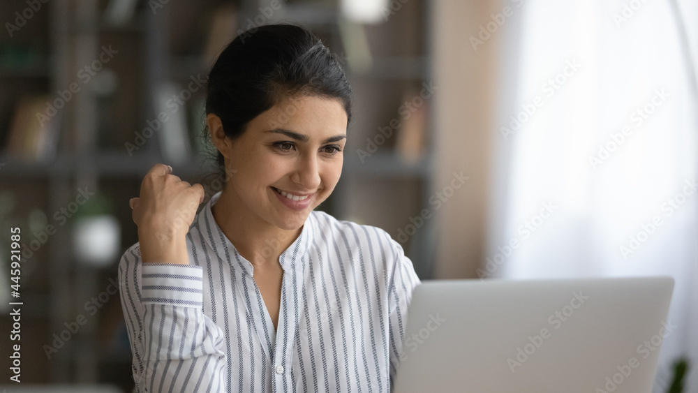 Smiling young Indian woman businesswoman work online on laptop at home office, consult client on web. Happy millennial mixed race female student study distant on computer. Technology concept.
