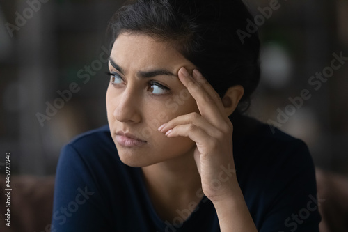 Pensive unhappy young Indian woman look in distance thinking pondering of life problems. Thoughtful millennial mixed race female feel worried anxious about relations. Dilemma  solution concept.