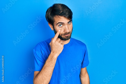 Young hispanic man wearing casual clothes pointing to the eye watching you gesture, suspicious expression