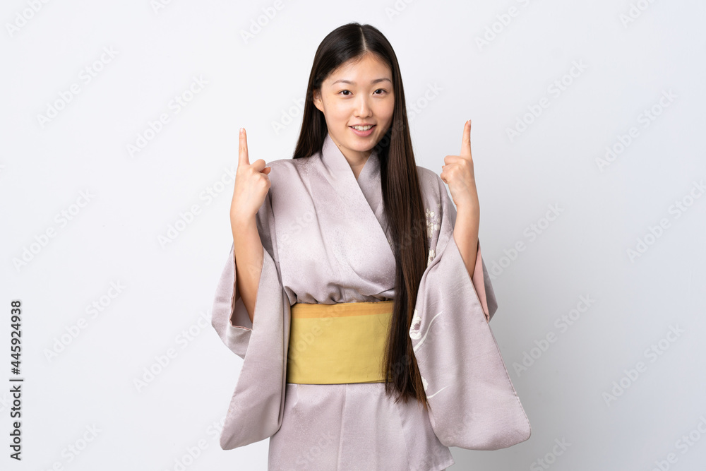 Young Chinese girl wearing kimono over isolated background pointing up a great idea Young Chinese girl wearing kimono over isolated background pointing up a great idea