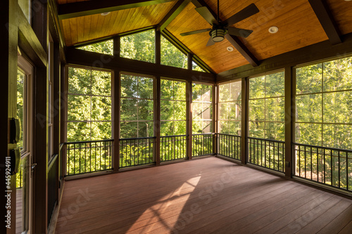 Modern new screened porch with plastic windows and composite floor with summer woods in the background. photo