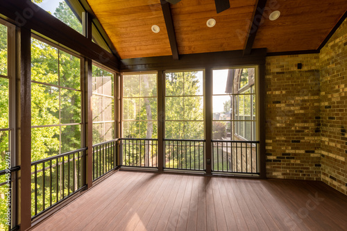 Modern new screened porch with plastic windows and composite floor with summer woods in the background.