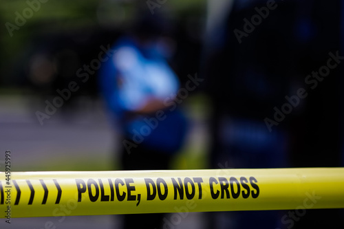 Shallow depth of field (selective focus) image with Police plastic tape reading Police, Do not cross, at a crime scene.