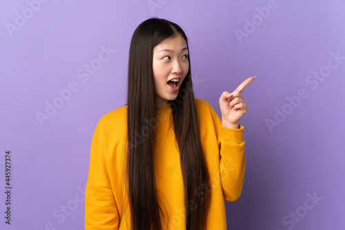 Young Chinese girl over isolated purple background intending to realizes the solution while lifting a finger up © luismolinero