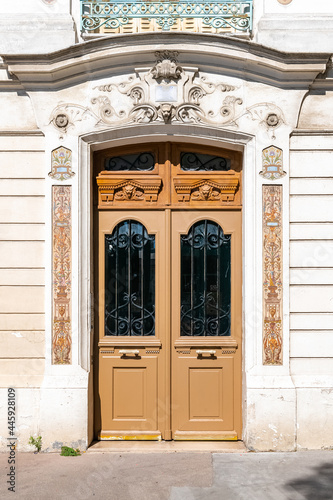 Paris, an ancient wooden door, beautiful decorated facade in the 10th arrondissement 