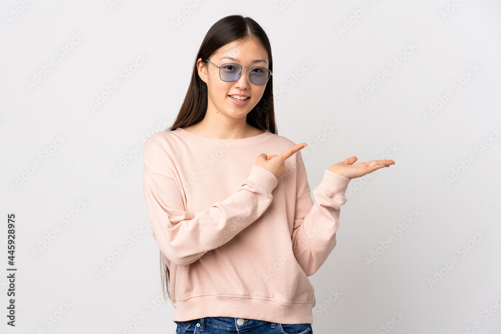 Young Chinese girl over isolated white background holding copyspace imaginary on the palm to insert an ad Young Chinese girl over isolated white background holding copyspace imaginary on the palm to insert an ad