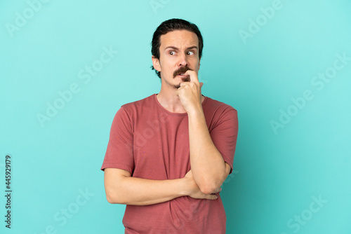 Young caucasian man isolated on blue background nervous and scared
