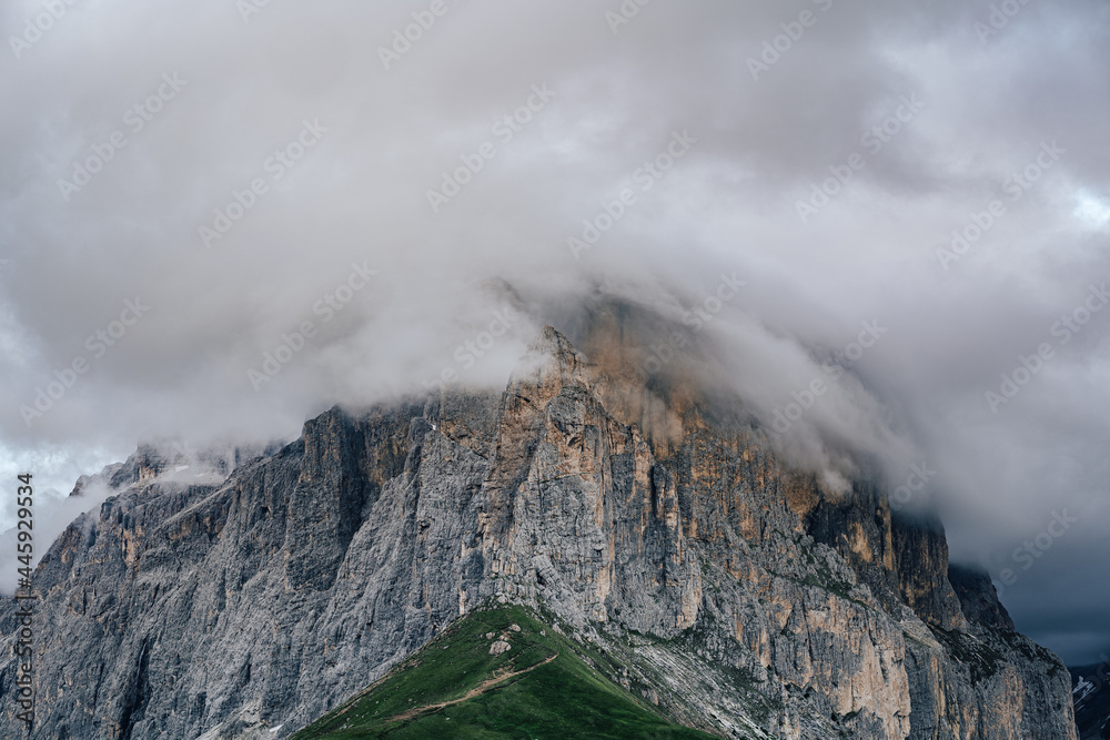 The Sella Group and Sella Towers in the motion blurred clouds. Evening view of high rock walls and towers of Sella group from Sella pass. Clouds and alpine meadows. Dolomites.