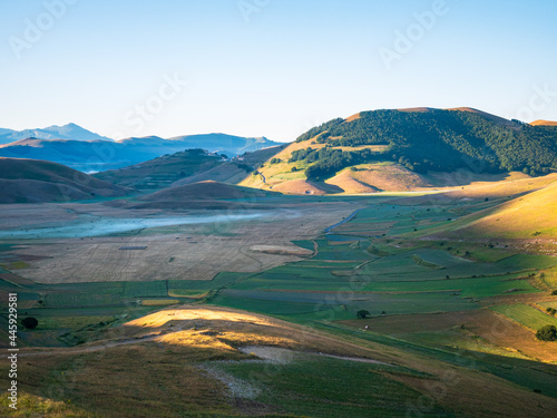 Sunrise over blooming cultivated fields, famous colourful flowering plain in the Apennines, Castelluccio di Norcia highlands, Italy. Agriculture of lentil crops.