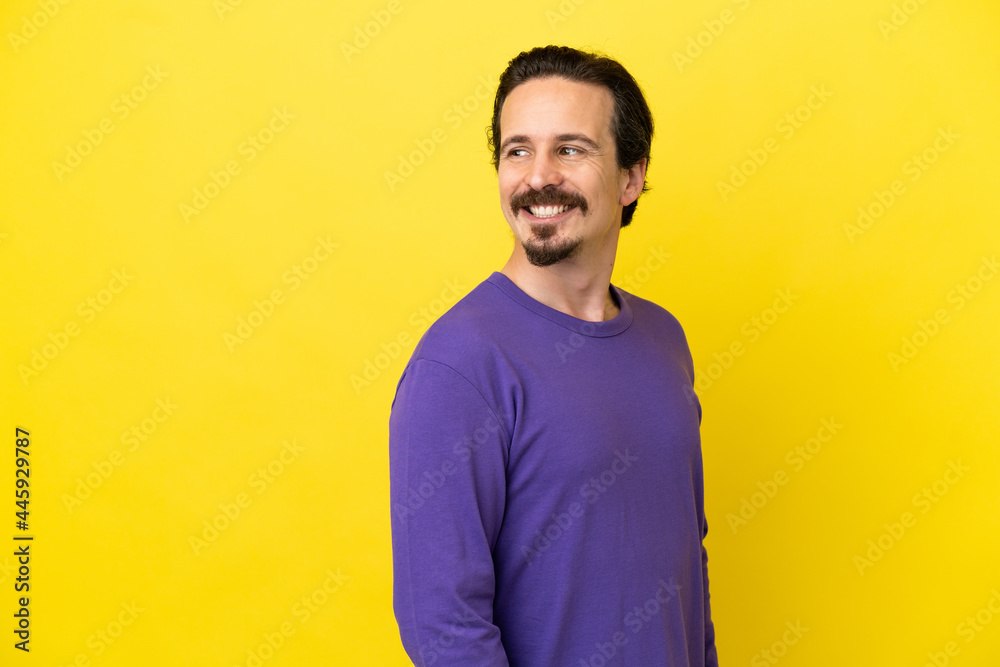Young caucasian man isolated on yellow background looking to the side and smiling Young caucasian man isolated on yellow background looking to the side and smiling