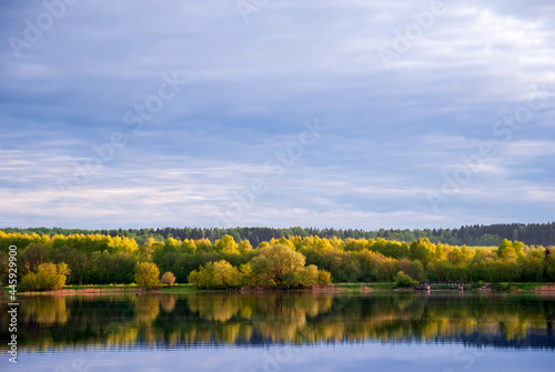 Autumn landscape with lake, trees with yellow leaves and sky with beautiful clouds.
