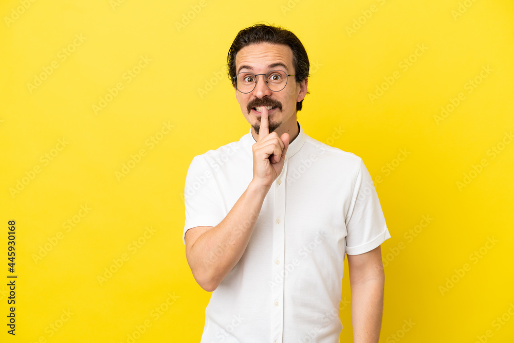 Young caucasian man isolated on yellow background showing a sign of silence gesture putting finger in mouth Young caucasian man isolated on yellow background showing a sign of silence gesture putting finger in mouth