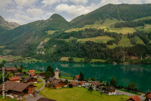 Swiss village Lungern with its traditional houses and old church tower Alter Kirchturm along lovely emerald green lake Lungerersee, canton of Obwalden, Switzerland - Swiss Alps, Brunig Pass photo