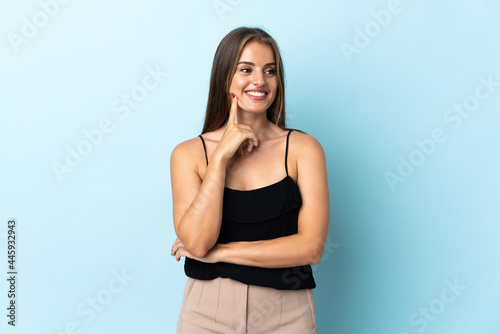 Young Uruguayan woman isolated on blue background thinking an idea while looking up © luismolinero