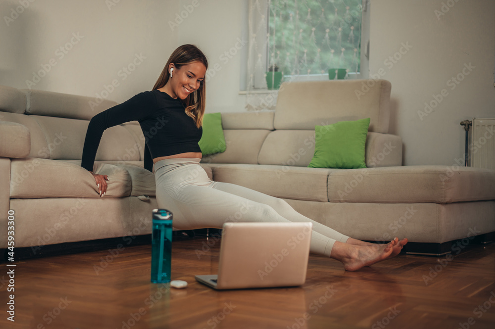 Obraz premium Young attractive woman using a laptop while training at home