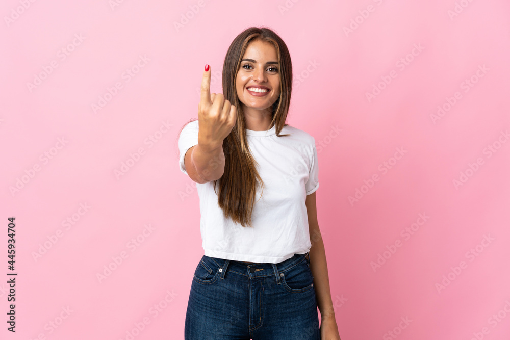 Young Uruguayan woman isolated on pink background doing coming gesture Young Uruguayan woman isolated on pink background doing coming gesture