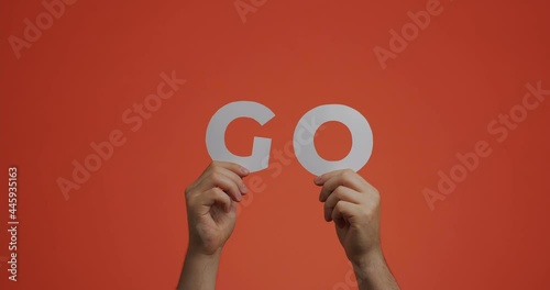 Hands raising up showing word go of english language. Man shows motivational phrase made of carved paper for blog photo