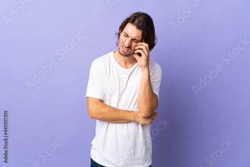 Young handsome man isolated on purple background with headache