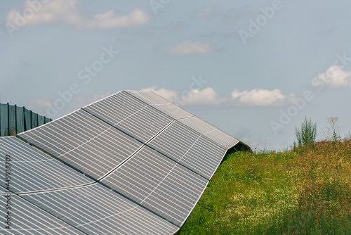 Solar  photovoltaic power station located on the hill. Green pasture grass and blue skies and white clouds create a fresh and ecological image.