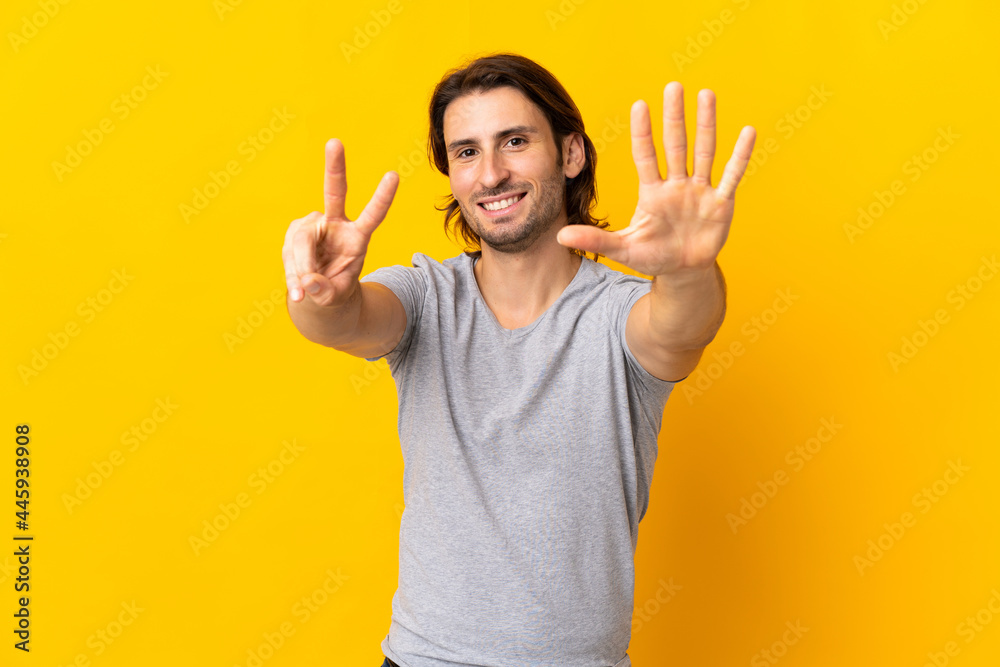 Young handsome man isolated on yellow background counting seven with fingers Young handsome man isolated on yellow background counting seven with fingers