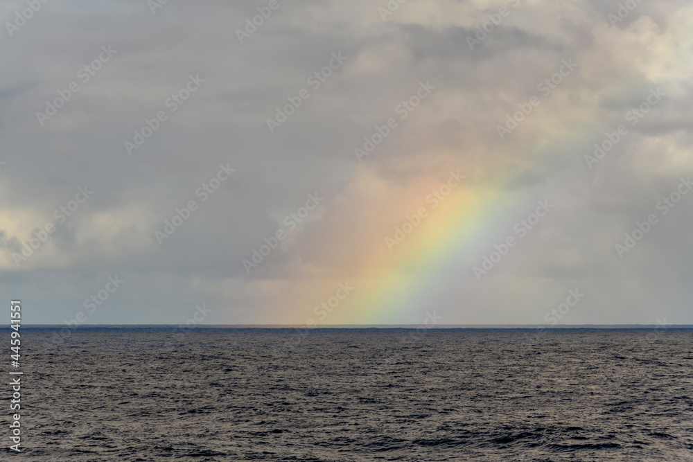 Rainbow at sea. Seascape, blue sea. Calm weather. View from vessel.  