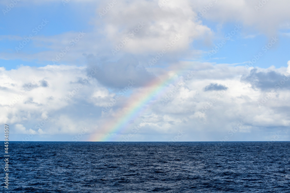 Rainbow at sea. Seascape, blue sea. Calm weather. View from vessel.  
