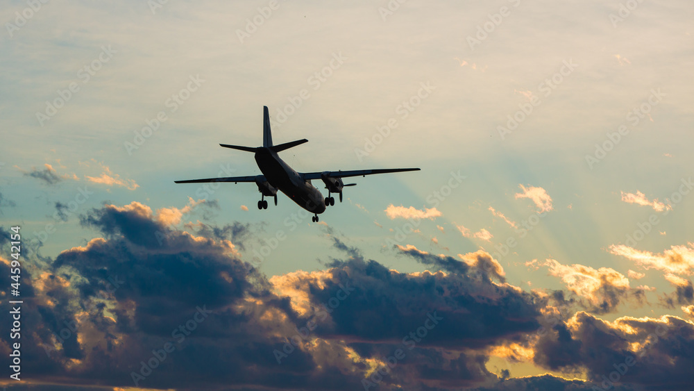 Fototapeta premium The plane is landing against the backdrop of a dramatic sky at sunset. airlines, flight, travel, tourism, trip.