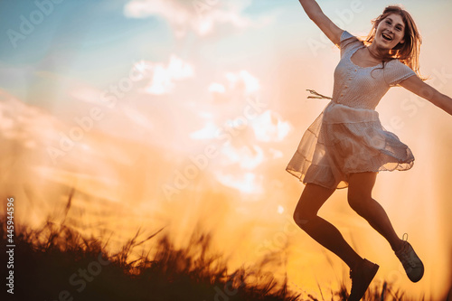 Outdoors photo of young, teen, ginger girl jumping. Copy space