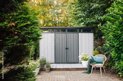 Gray garden shed in summer. Lots of pots of flowers next to a plastic garden shed. Relax in the garden. Big garden in Germany 