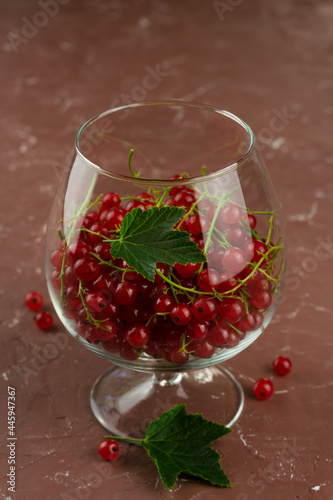 Red currant in a glass on brown background