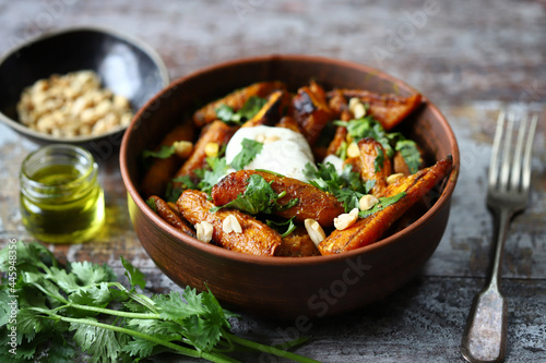 Baked carrots in a bowl with cream cheese, cilantro and nuts.