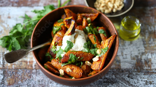 Baked carrots in a bowl with cream cheese, cilantro and nuts.
