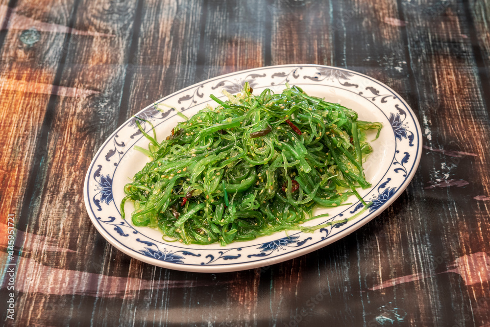 Tray of wakame seaweed salad with cayenne and sesame seeds on dark table. Tray of wakame seaweed salad with cayenne and sesame seeds on dark table.