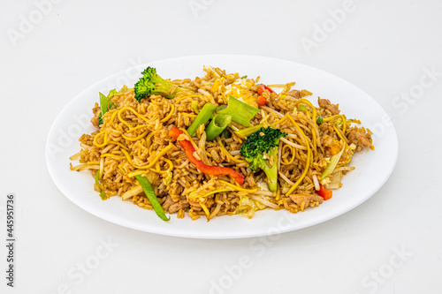 Fried rice with noodles, sautéed vegetables and chicken pieces with soy sauce and sprouts, chopped chives and white tray