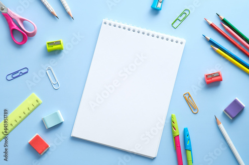 School supplies and notepad on blue background. Back to school concept. Flat lay, top view, overhead.
