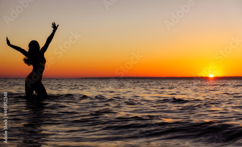 The girl swims in the sea, splashes in the water at sunset. Relaxation and happy pastime. Summer vacations.