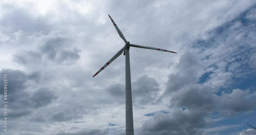 rotating blades of a windmill propeller on blue sky background with clouds. Wind power generation. Pure green energy. rotating blades of a windmill propeller on blue sky background with clouds. Wind power generation. Pure green energy.