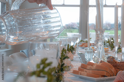 Man Pouring Water at a Table Set for Many People