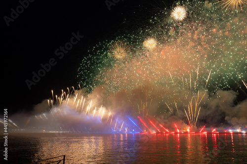 Festive colorful fireworks and illumination in dark sky with beautiful reflection in water. Holiday SCARLET SAILS