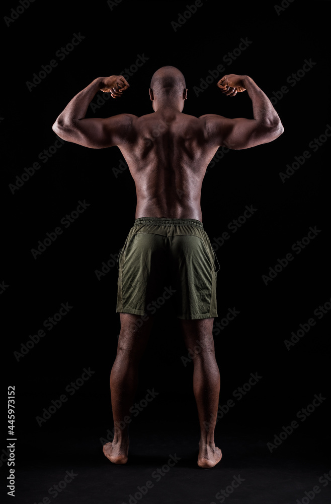 Rear view of a black muscular man flexing arm muscles on a black background Rear view of a black muscular man flexing arm muscles on a black background